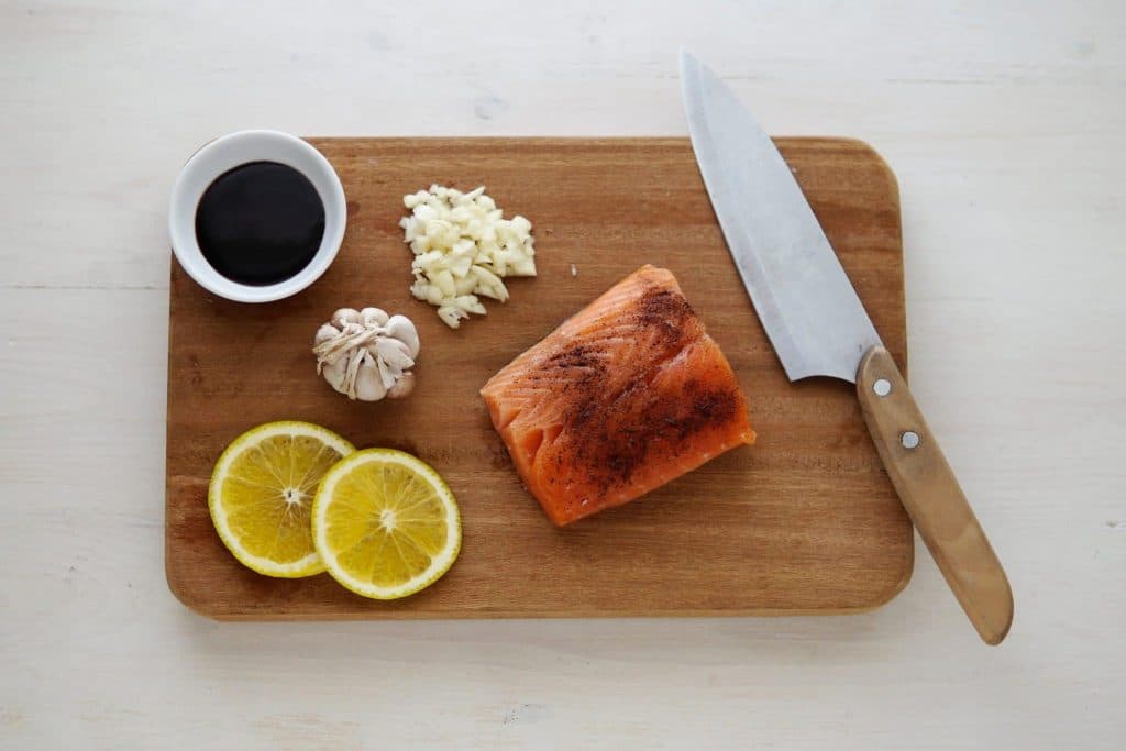 Salmon, lemon, garlic cloves, garlic chopped up, knife on cutting board, soy sauce