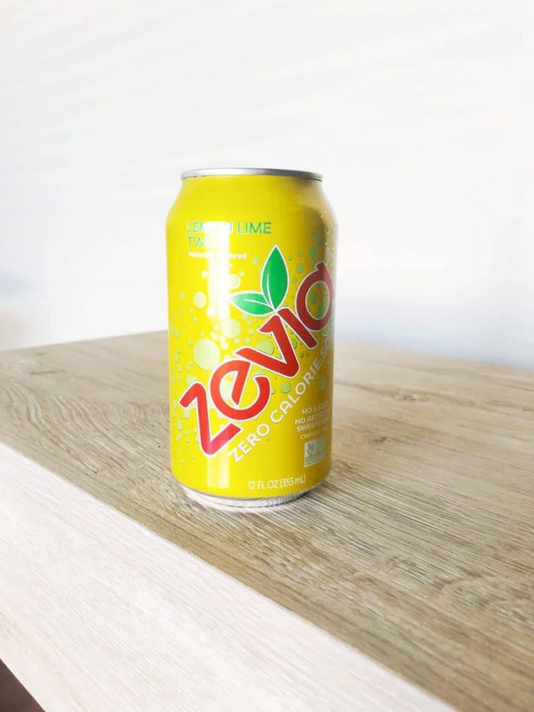 Zevia zero calorie lemon lime flavor soda sitting on tan desk with white wall