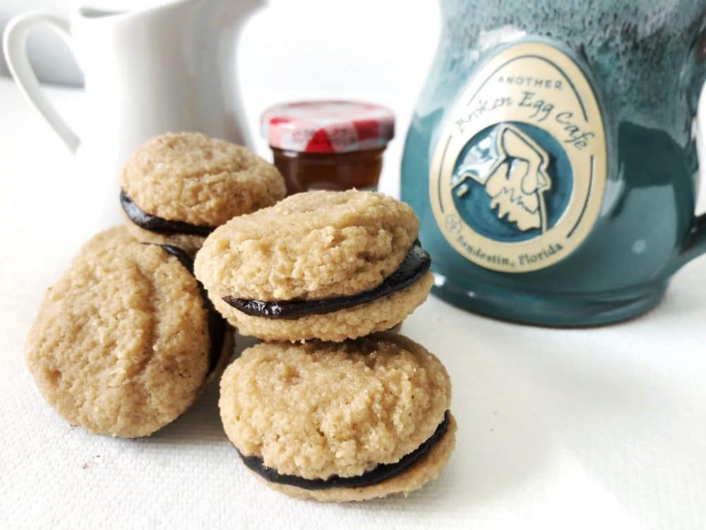 mocha-espresso macarons with teal coffee cup, creamer, and jelly in the background