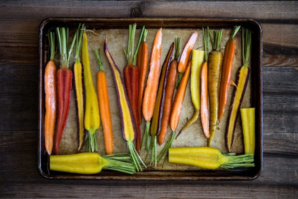 Orange carrots, yellow carrots, red carrots with olive oil on a roasting pan