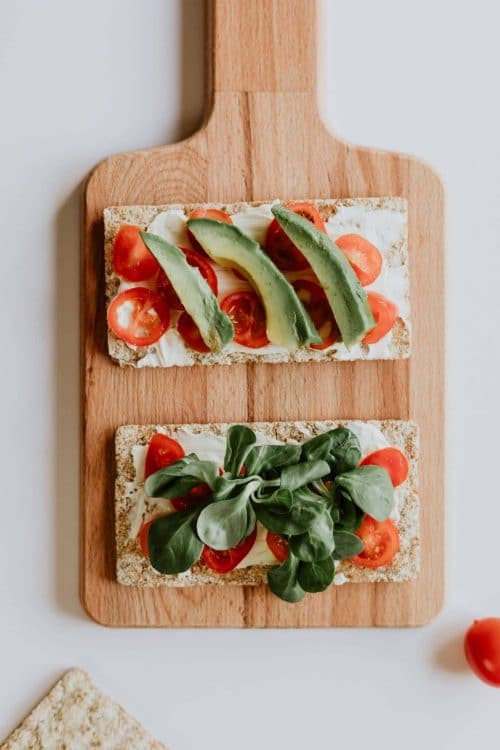 cutting board with fiber flatbread with cream cheese, spinach, avocado, and tomatoes