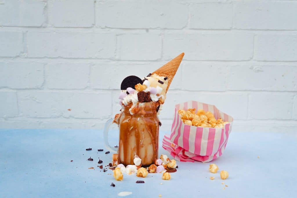 chocolate ice cream in a mason jar with ice cream cone on top with caramel popcorn nearby