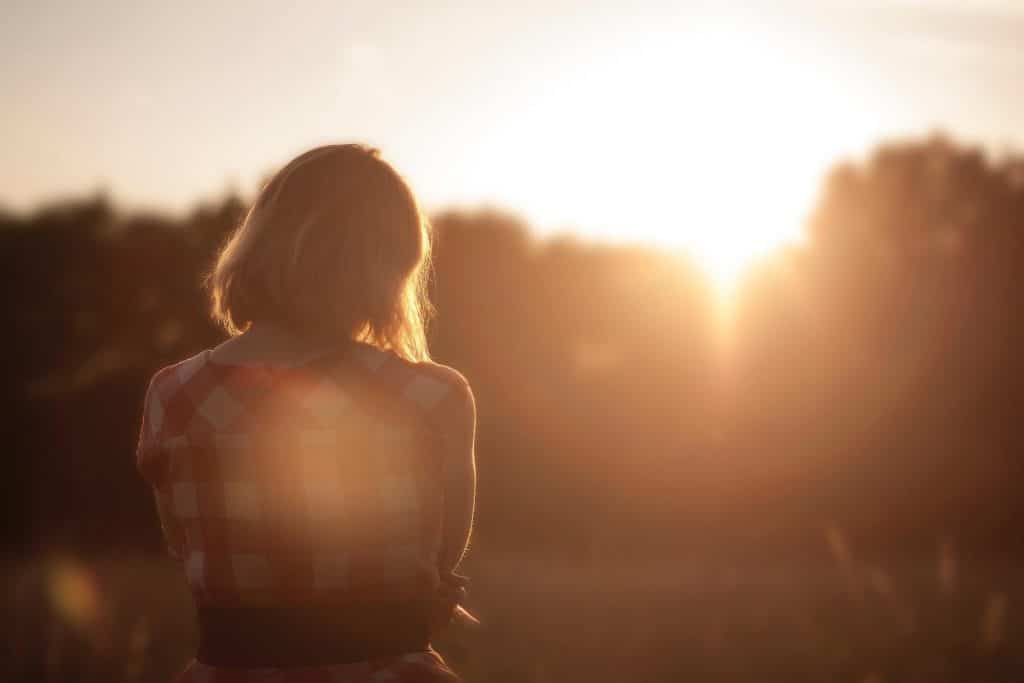 blonde woman with checkered red shirt staring at sunrise, out of a funk