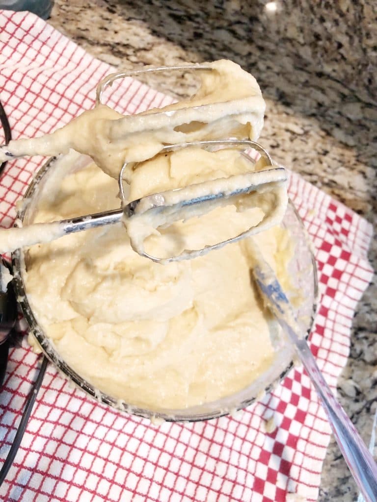 choux pastry donut dough in glass bowl with hand mixer on kitchen counter