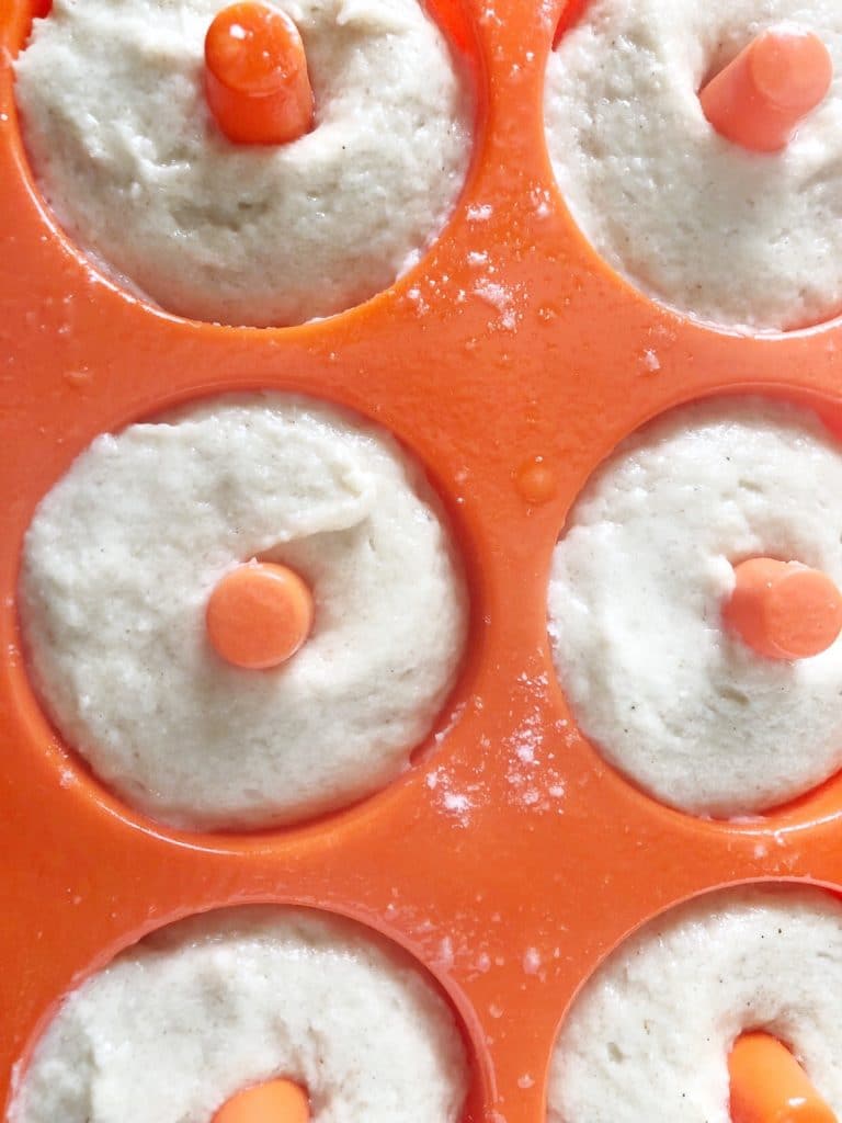 orange silicone donut pan with choux pastry dough piped in ready to bake
