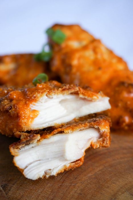 chicken tender cut in half close-up topped with green onions