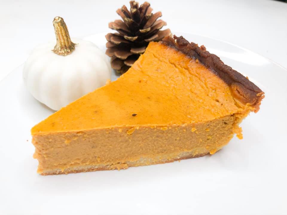 pumpkin pie with white pumpkin and pinecone nearby