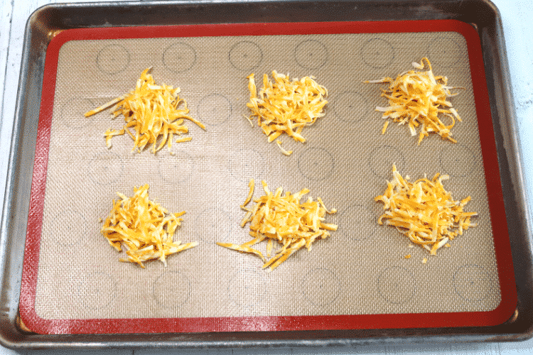 Shredded cheese mounds on silicone baking mat ready for the oven