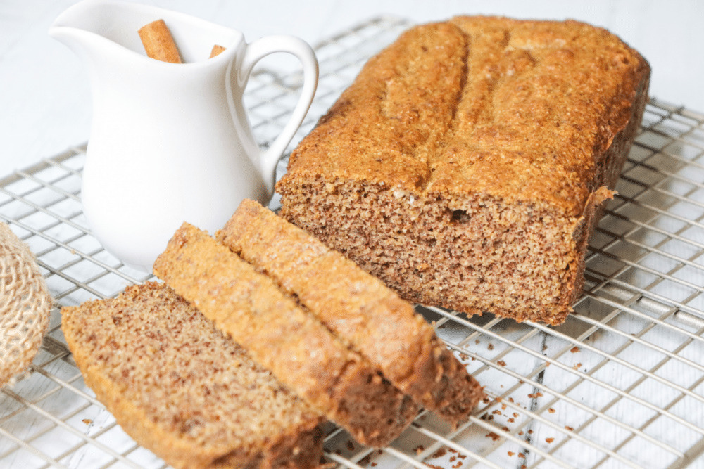 spice cake sliced on cooling rack with cinnamon sticks nearby