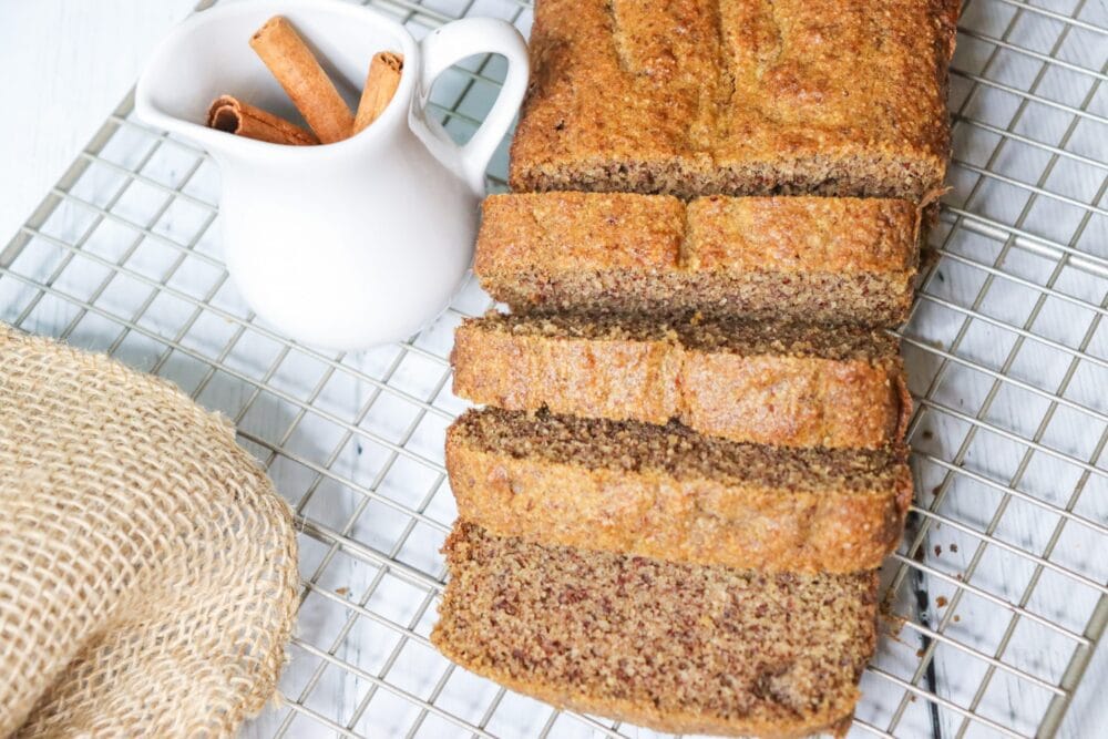 spice cake multiple slices overhead on cooling rack with cinnamon sticks nearby