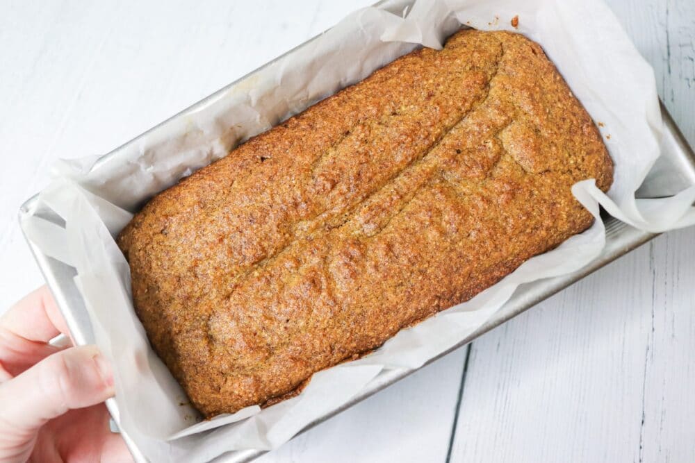 holding spice cake loaf in hand in loaf pan