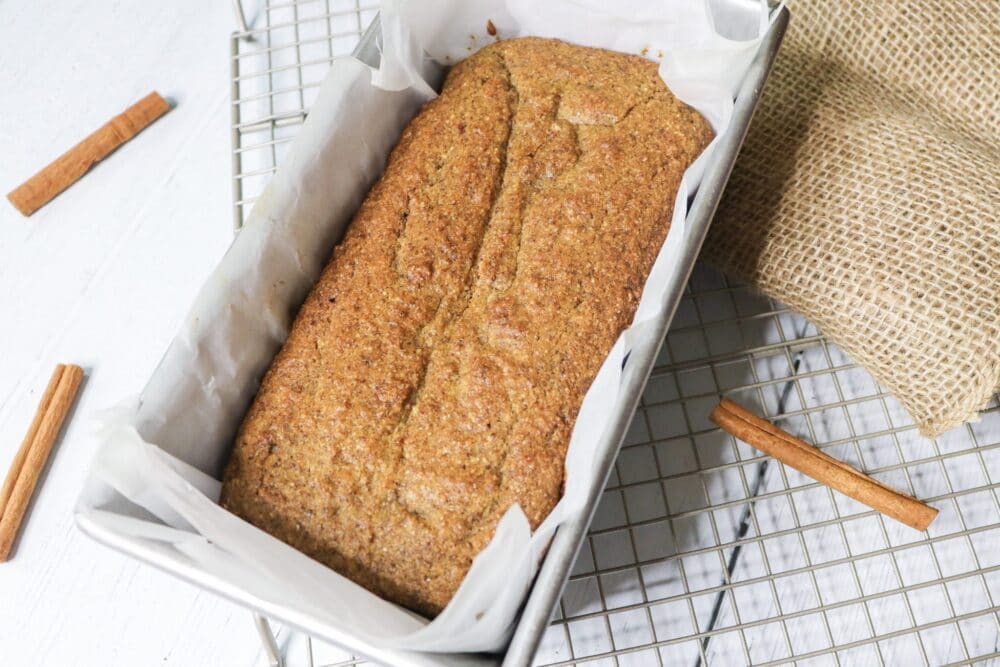 whole spice cake loaf overhead shot on cooling rack with cinnamon sticks nearby