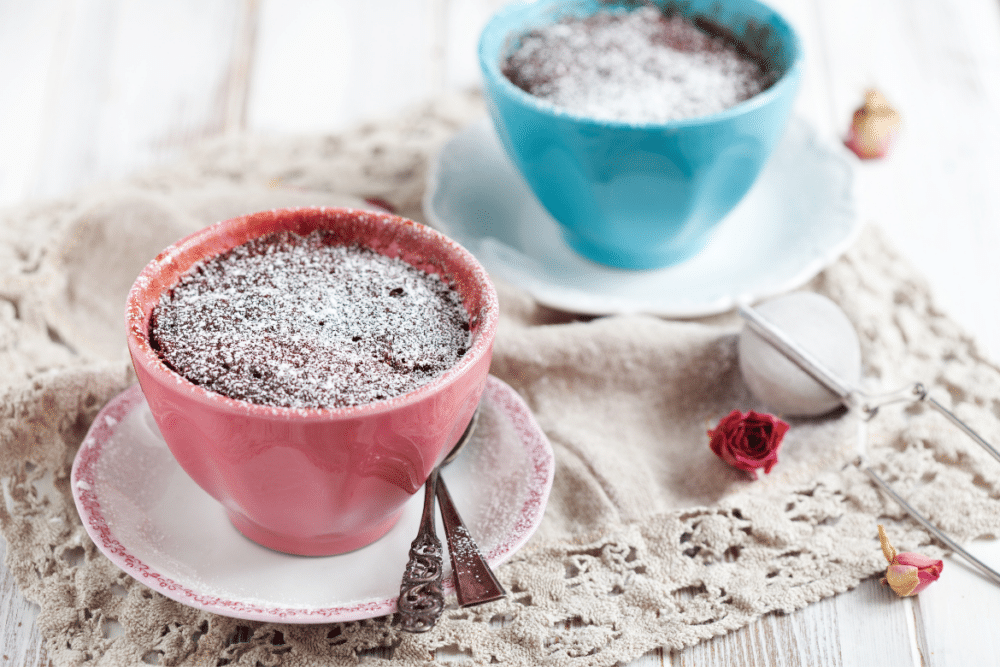 two chocolate mug cakes in blue and pink mugs