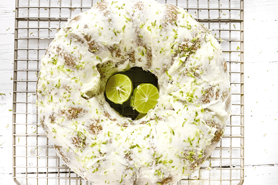 keto lime pound cake with limes and low carb cream cheese frosting and lime zest on top