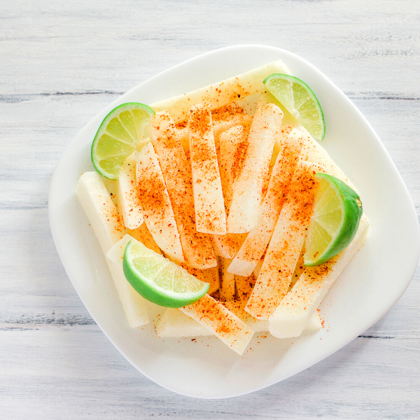 raw jicama fries sprinkled with seasoning and sliced limes