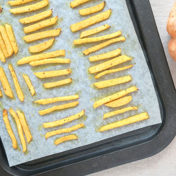 crispy jicama fries on baking sheet lined with parchment paper fresh out of the oven