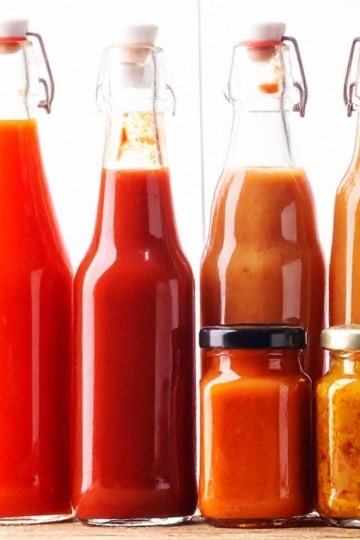 various hot sauces in tall glass bottles lined up