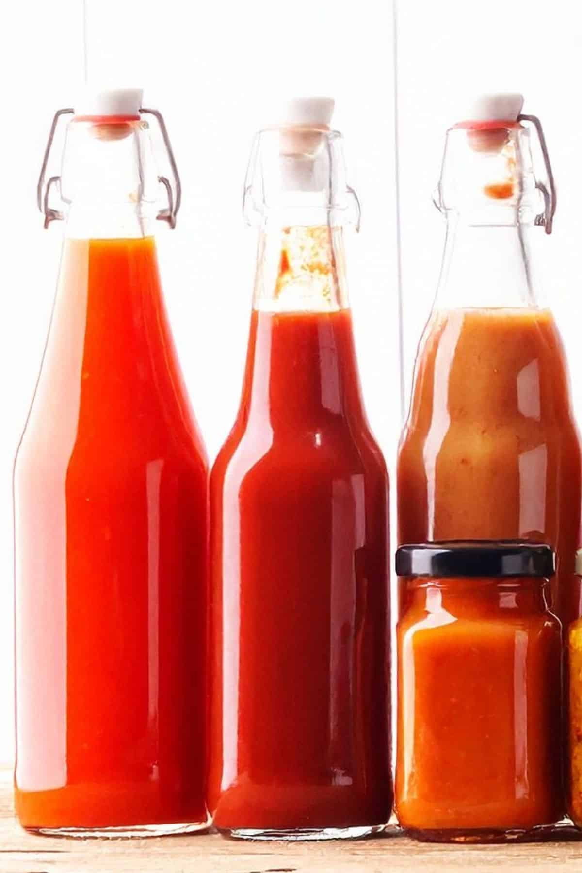 various hot sauces in tall glass bottles lined up
