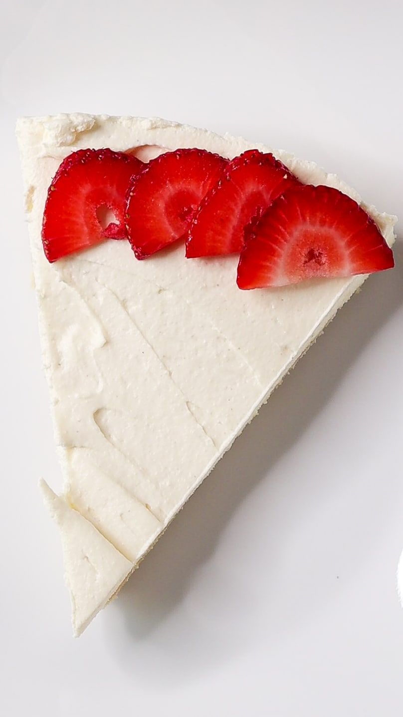 one slice of no-bake keto cheesecake with sliced strawberries on white plate