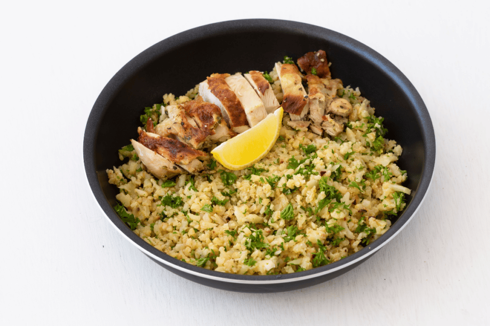 low carb riced cauliflower in a bowl with pork and lemon