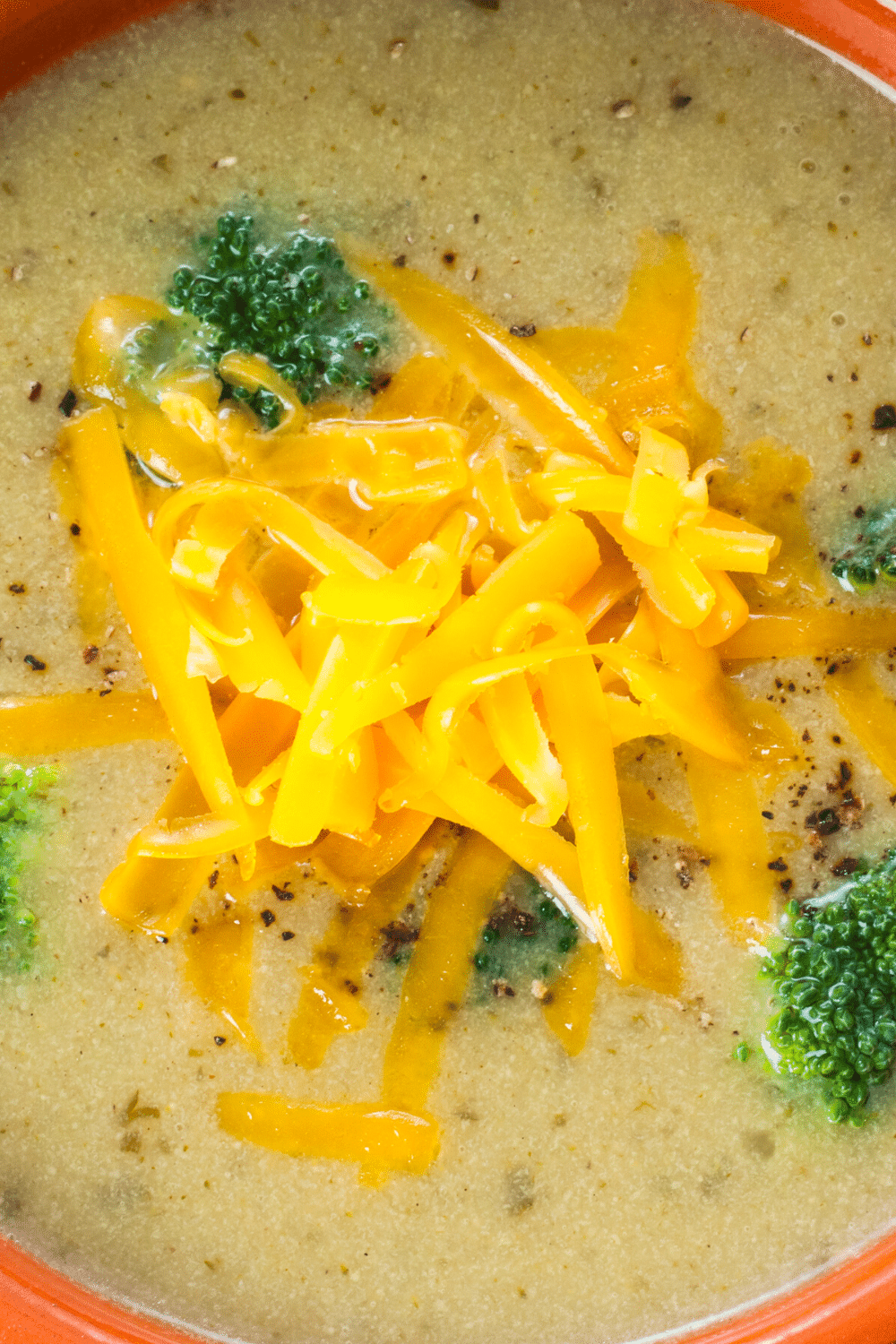 A comforting bowl of creamy broccoli and cheddar soup, brimming with tender broccoli florets and a rich cheddar cheese base. The soup showcases vibrant green broccoli immersed in a velvety, smooth texture, with melted cheddar cheese adding a delightful richness and depth of flavor. The soup is garnished with a sprinkle of shredded cheddar cheese and perhaps a few broccoli florets, providing a visually appealing presentation. This soul-warming soup is a perfect combination of wholesome ingredients, making it a hearty and satisfying choice for any occasion.