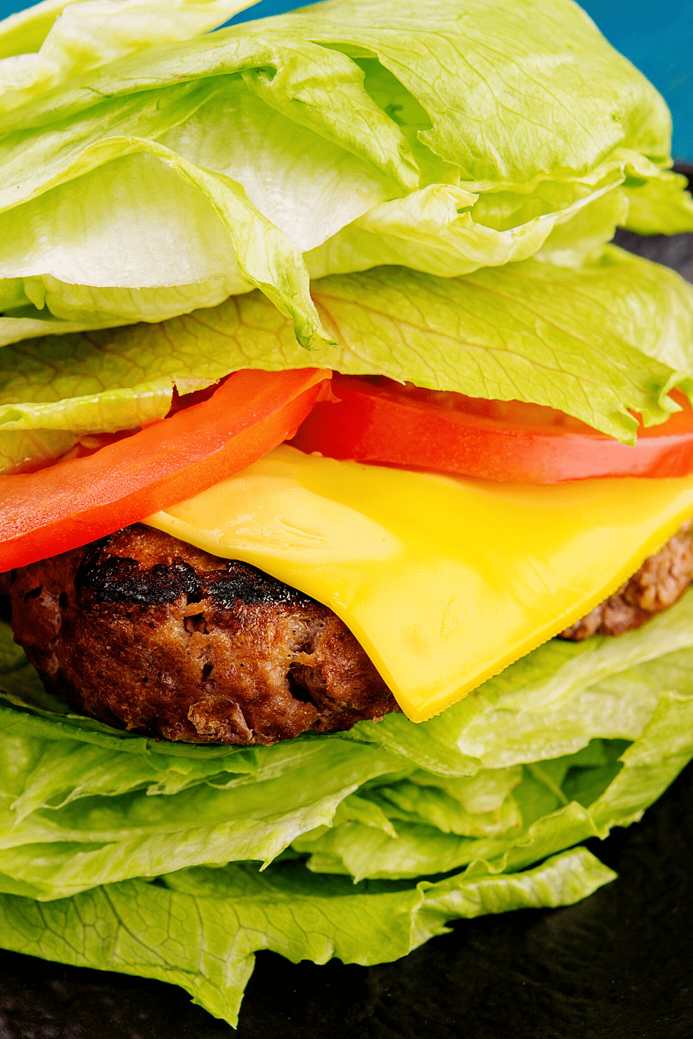 A cheeseburger lettuce wrap featuring a juicy grilled beef patty wrapped in a crisp and fresh lettuce leaf. The succulent beef patty is cooked to perfection, topped with melted cheese, and adorned with classic burger toppings such as sliced tomatoes, red onions, and pickles. The lettuce leaf acts as a flavorful and low-carb alternative to a traditional burger bun, providing a refreshing crunch and allowing the ingredients to shine. This delightful cheeseburger lettuce wrap offers a healthier twist on a beloved classic, ideal for those seeking a lighter option without compromising on taste.