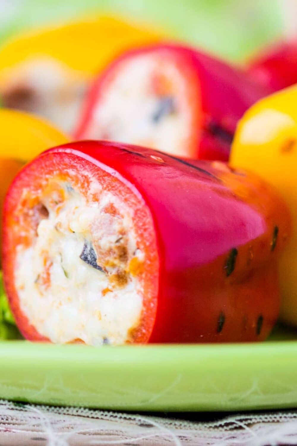 Closeup view of vibrant mini bell peppers generously stuffed with creamy cheese, highlighting the contrast between the colorful peppers and the rich, white cream cheese filling, serving as a tempting, keto-friendly appetizer