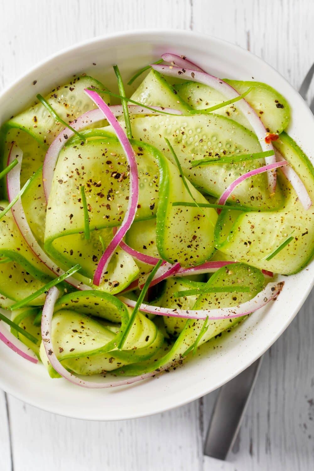 Crisp cucumber salad with thin cucumber slices and fresh dill, lightly dressed and served in a clear glass bowl, highlighting the refreshing, hydrating, and keto-friendly side dish, perfect for a hot summer day.