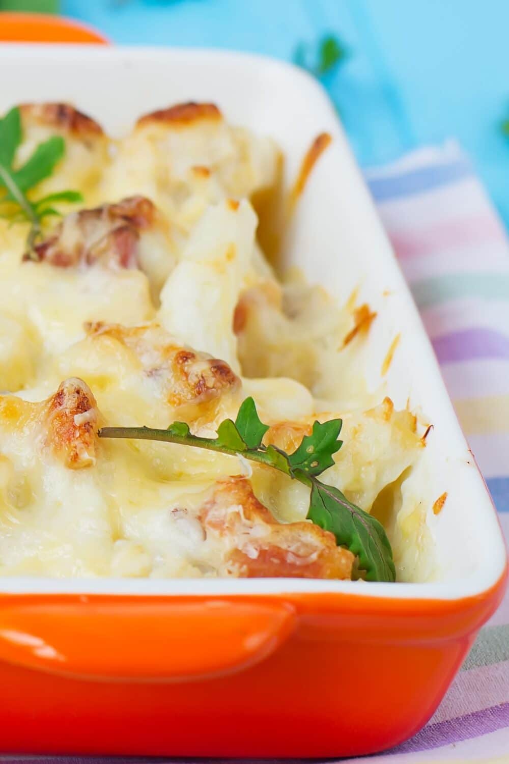 An appetizing cauliflower casserole dish, featuring a golden-brown crust and a creamy, cheesy interior. Fresh cauliflower florets are nestled in a rich sauce, seasoned with aromatic herbs and spices. The dish is topped with a sprinkle of breadcrumbs and melted cheese, creating a delectable and comforting meal.