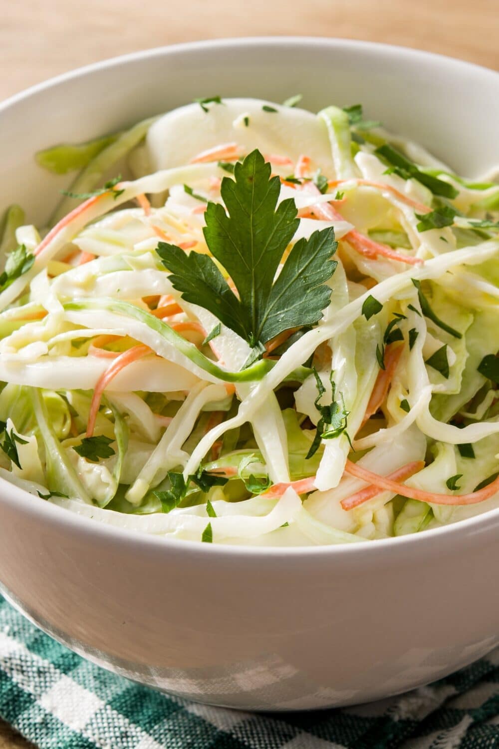 "A vibrant and refreshing coleslaw salad. Shredded cabbage and carrots create a colorful base, offering a satisfying crunch. The salad is dressed with a tangy and creamy dressing, perfectly balancing the flavors. Topped with a sprinkle of fresh parsley, this coleslaw is a perfect accompaniment to any meal, providing a crisp and refreshing burst of taste