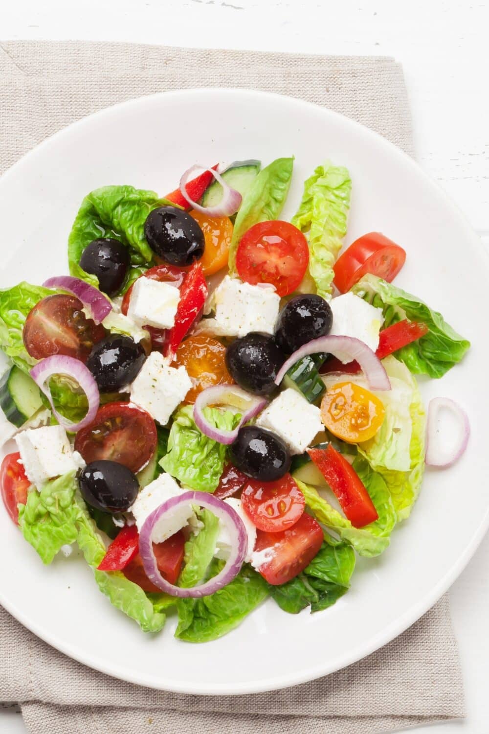 Greek Salad, a classic Mediterranean delight. Crisp lettuce leaves serve as the base, adorned with a colorful assortment of ingredients. Ripe tomatoes, refreshing cucumber slices, tangy Kalamata olives, and creamy feta cheese are generously scattered throughout the salad. The flavors are enhanced with a drizzle of extra virgin olive oil and a sprinkle of aromatic herbs. This vibrant salad offers a refreshing combination of textures and tastes, capturing the essence of Greek cuisine in every bite