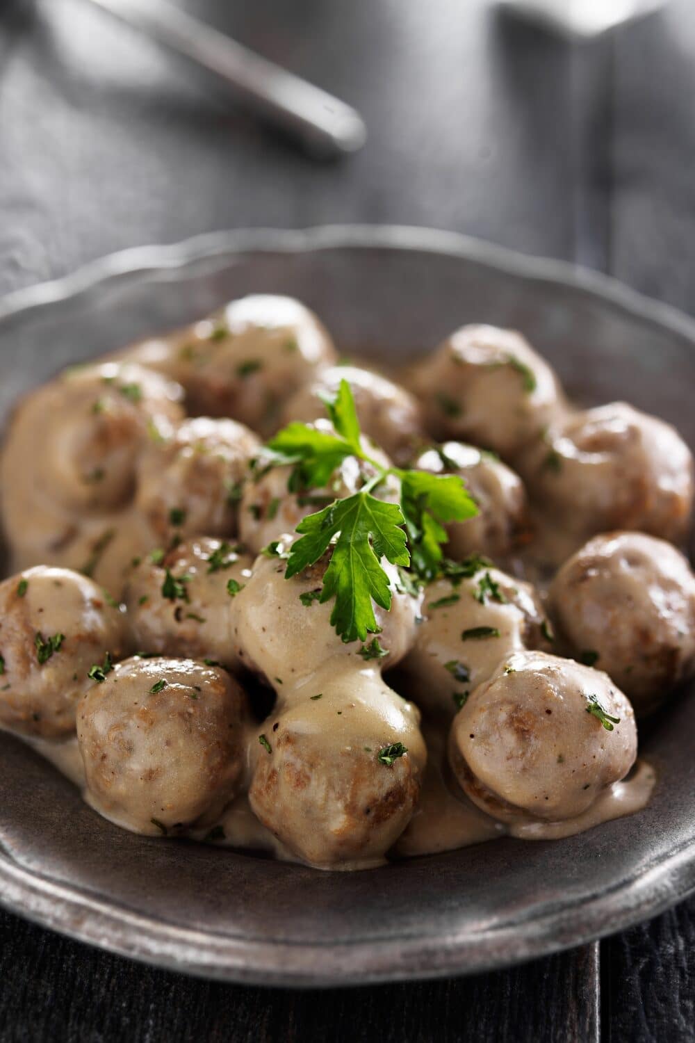 Swedish meatballs arranged elegantly on a plate, adorned with a garnish of fresh parsley. These tender and flavorful meatballs are a symphony of taste, featuring a delicate balance of seasoned ground meat and a creamy, savory sauce. The vibrant green parsley adds a touch of color and herbal freshness, inviting you to savor every bite of this beloved Swedish delicacy.