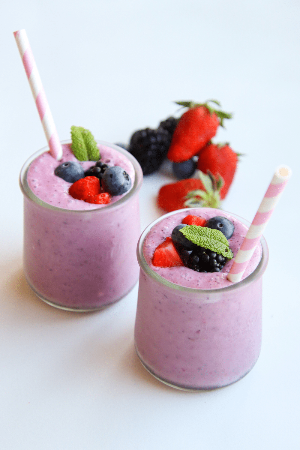 A vibrant berry-colored smoothie in a glass, topped with an assortment of fresh berries.