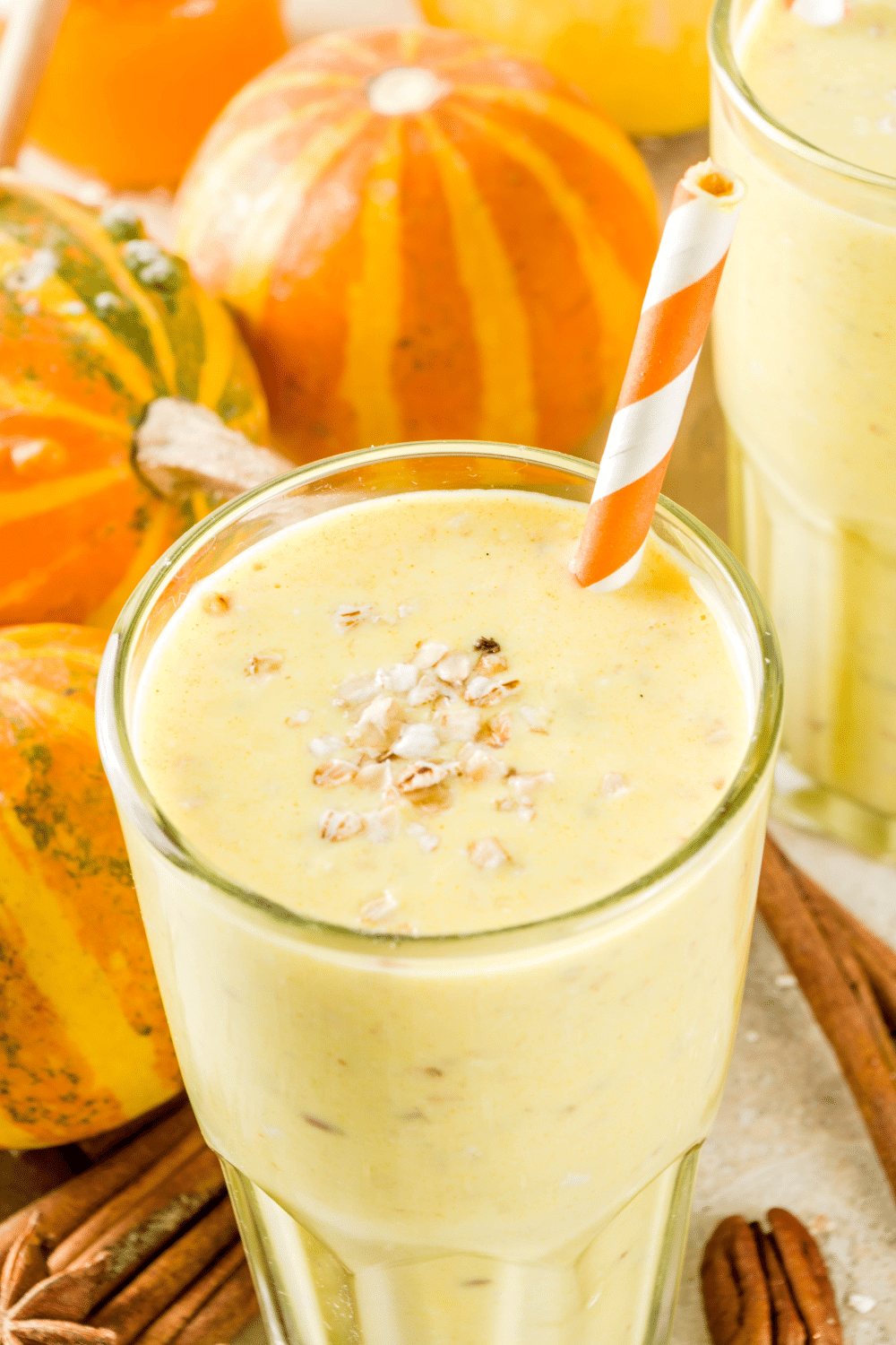 A tall glass of creamy pumpkin spice smoothie, topped with a sprinkle of nutmeg.