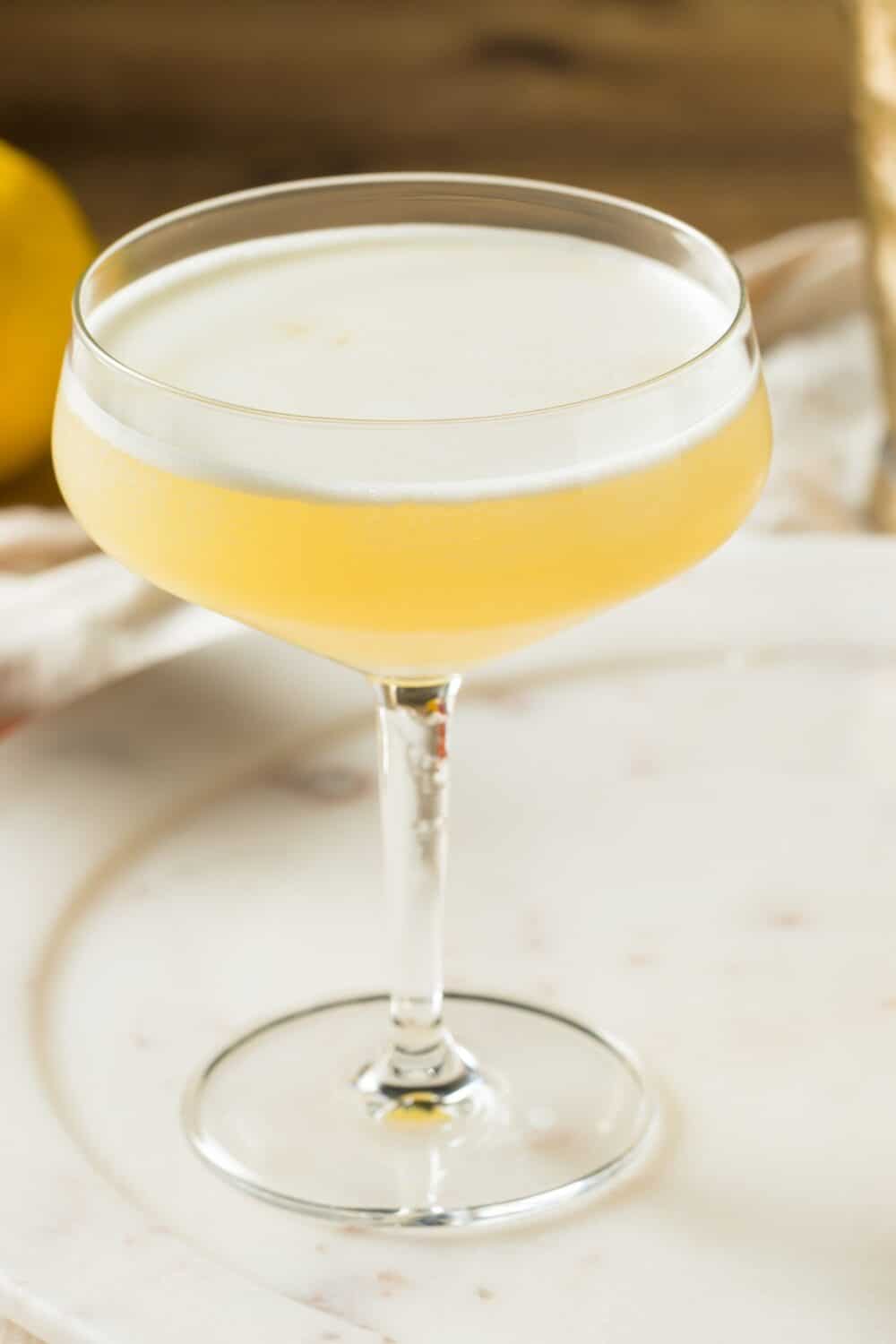 A golden-hued cocktail made with gin, fresh lemon juice, and a sugar-free honey syrup, shaken and strained into a glass.