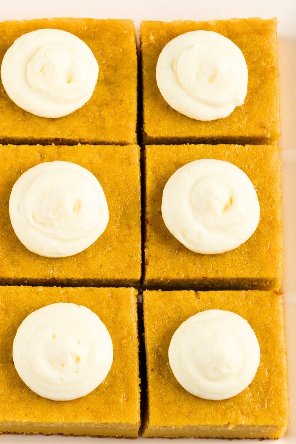 Squares of smooth crustless pumpkin pie on a plate, with a dollop of whipped cream.