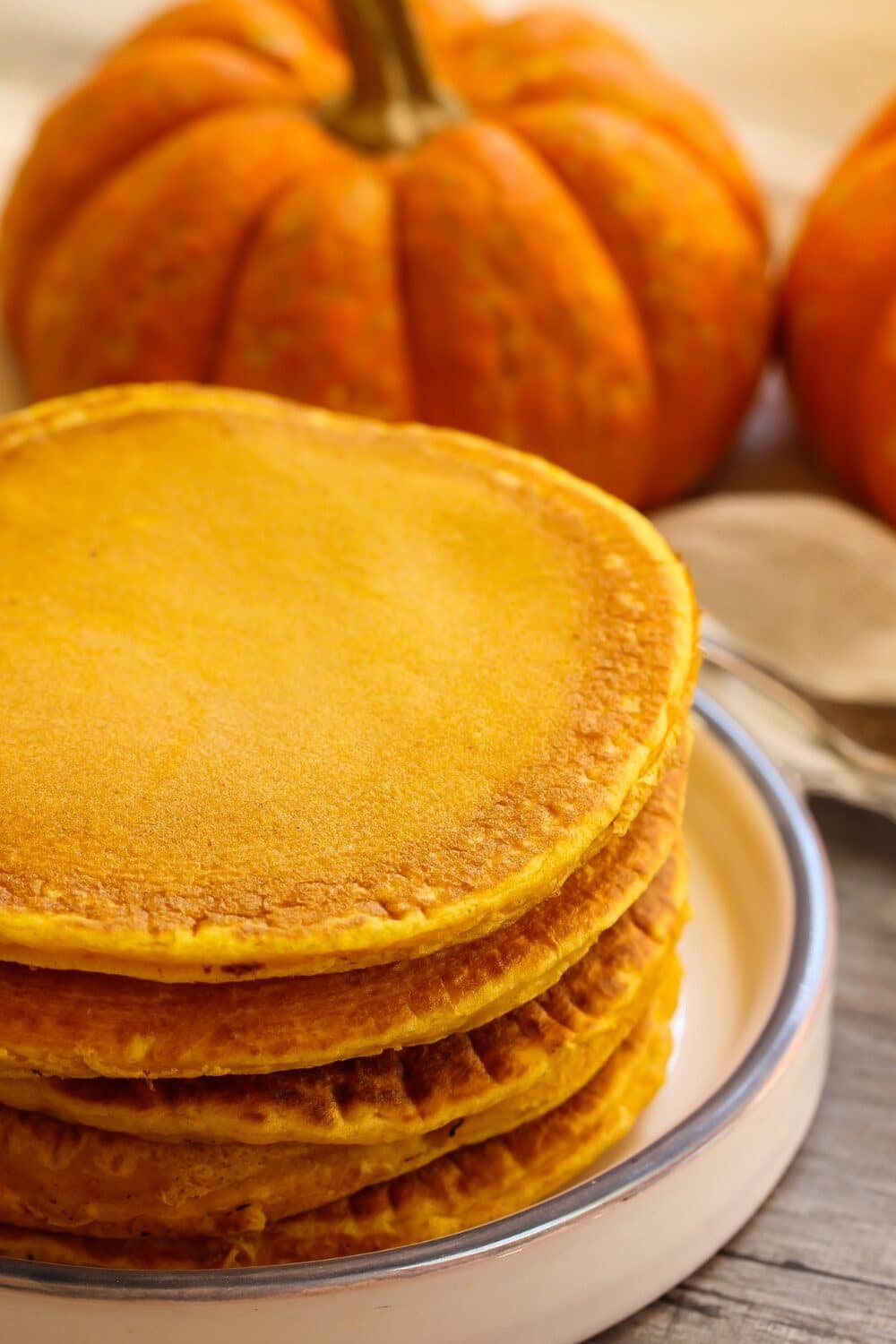 A stack of fluffy pumpkin pancakes, served on a white plate