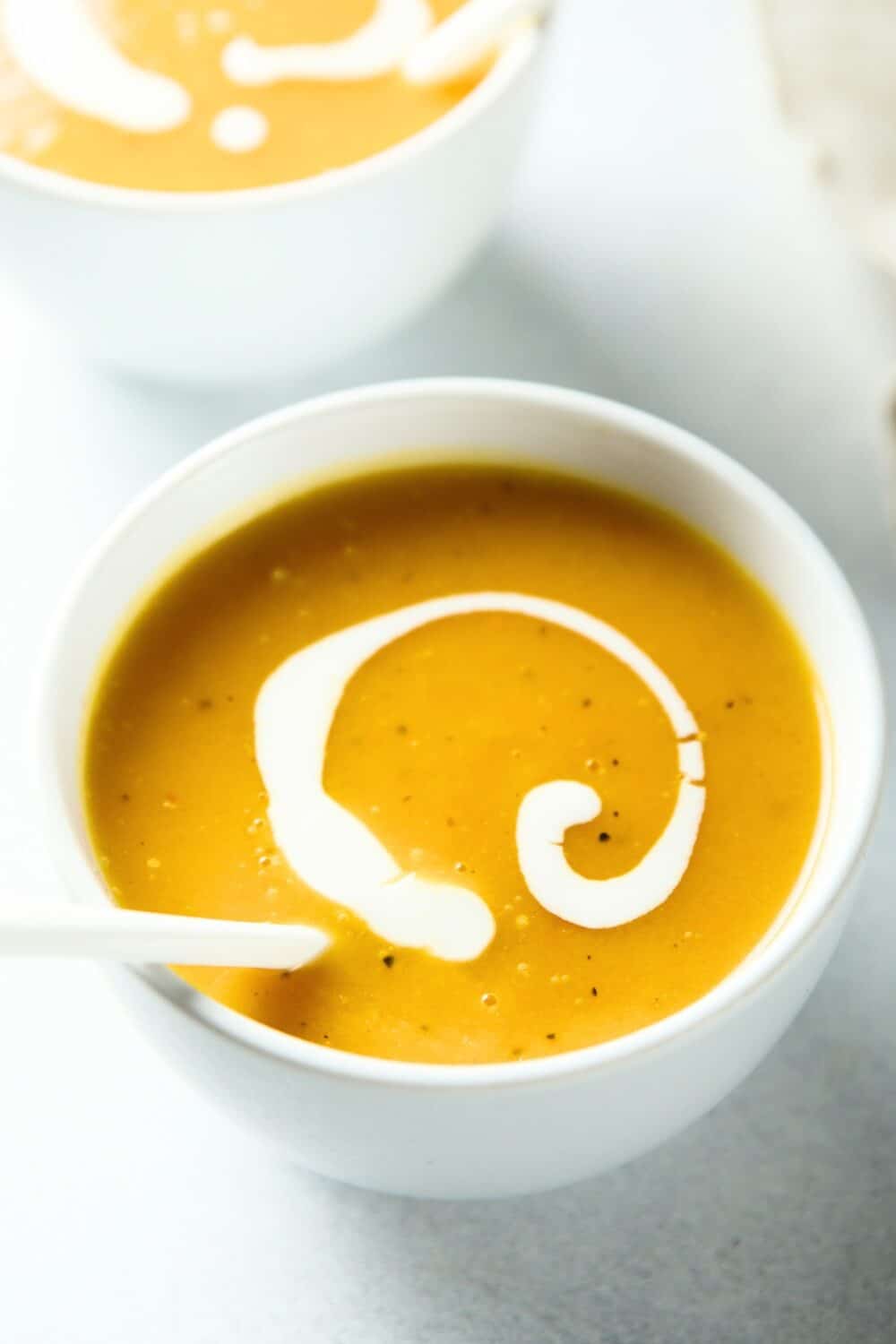 A bowl of creamy pumpkin soup garnished with fresh herbs and cream.
