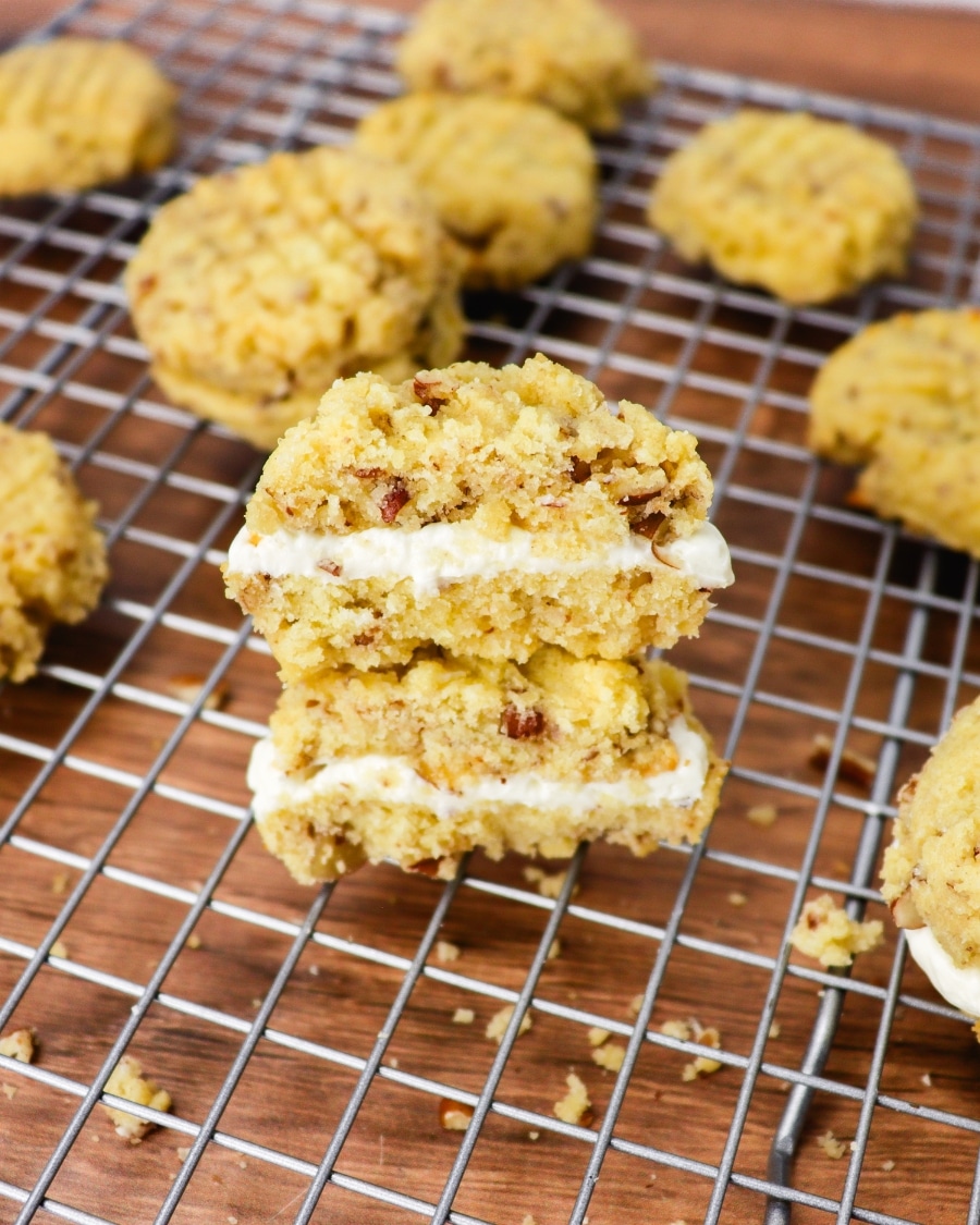 assembled keto pecan cookies with cream cheese filling displaying the middle layer on a wire cooling rack