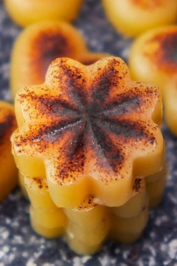 3 brown butter bites stacked on a black cutting board with other shape bites around it
