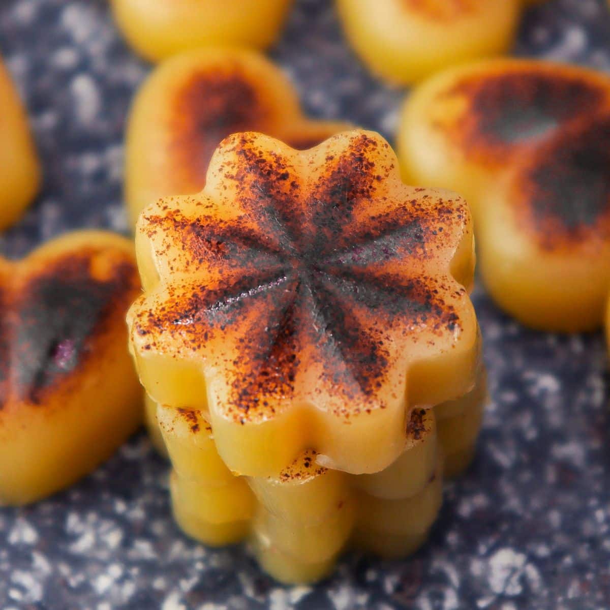 3 brown butter bites stacked on a black cutting board with other shape bites around it