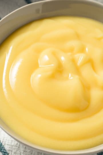 yellow carnivore diet pudding recipe in a white bowl with striped napkin underneath overhead view