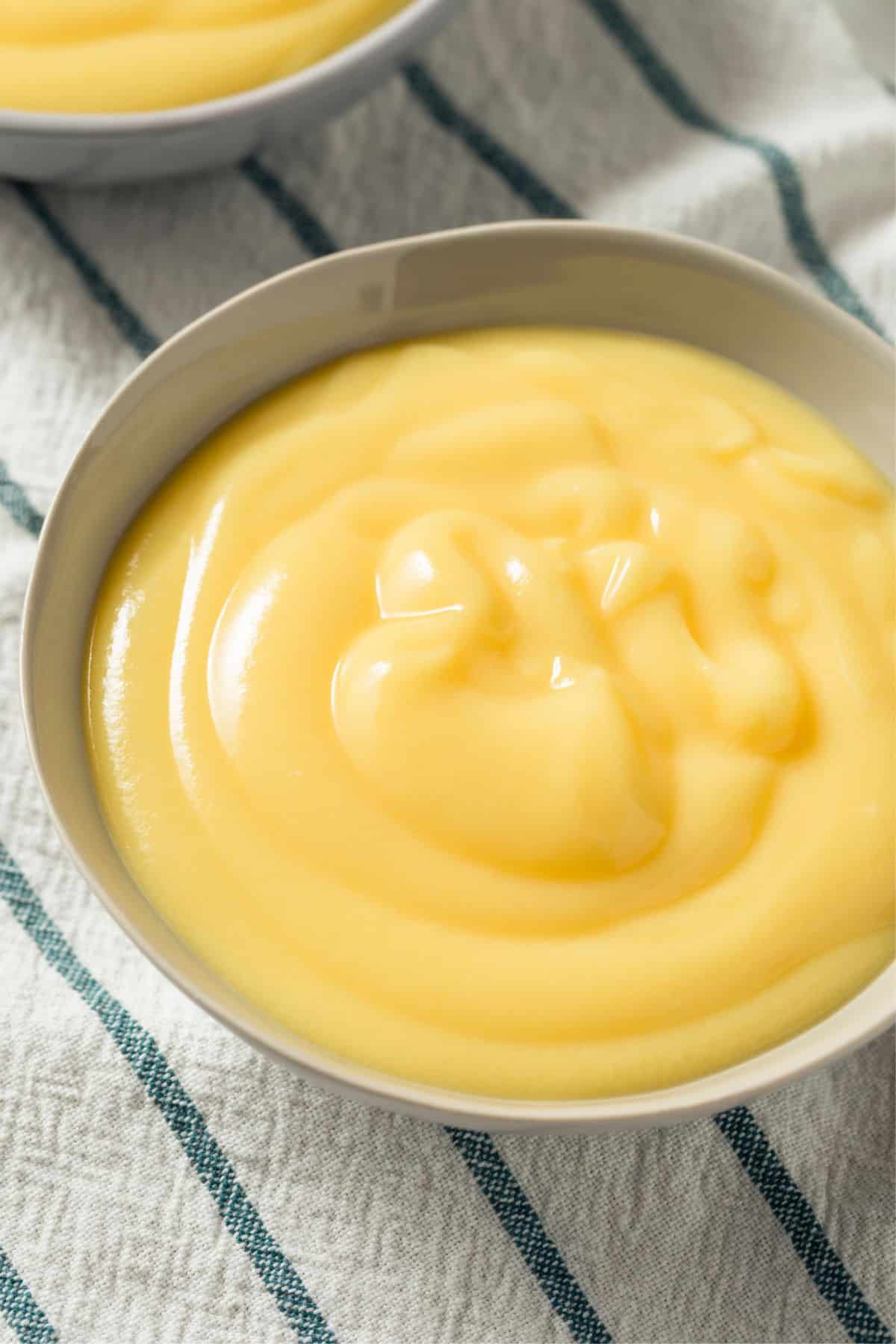 yellow carnivore diet pudding recipe in a white bowl with striped napkin underneath overhead view