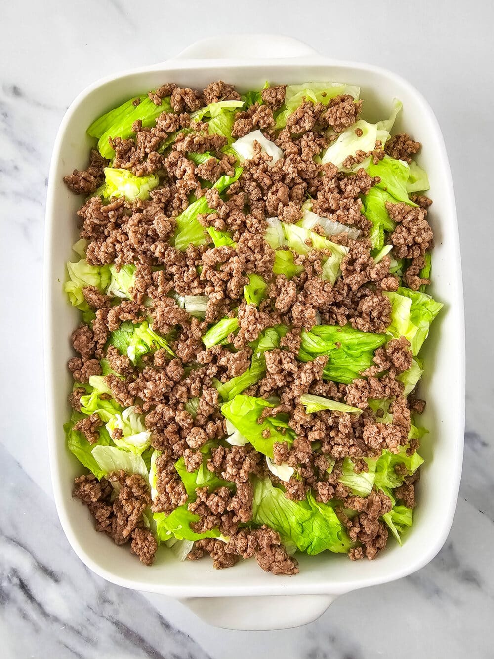 chopped lettuce and ground beef in a casserole dish
