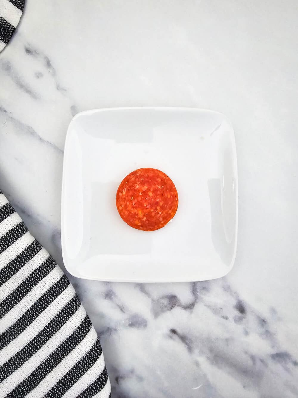 one single slice of pepperoni on a plate