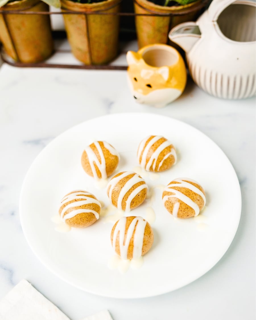 High Protein Cinnamon Roll Energy Bites on a plate with decorations in the background