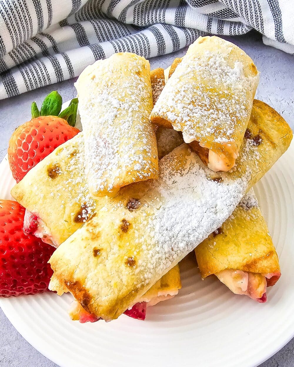 Keto Air Fryer Strawberry Cheesecake Roll Ups on a plate with strawberries