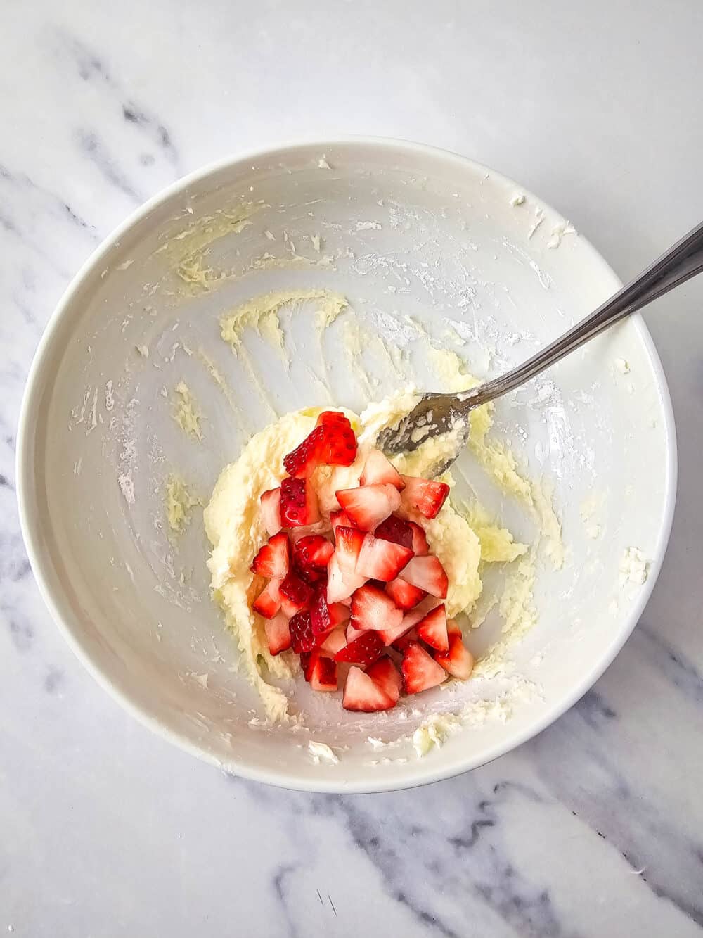 mixed cream cheese and sweetener in a bowl with strawberries added