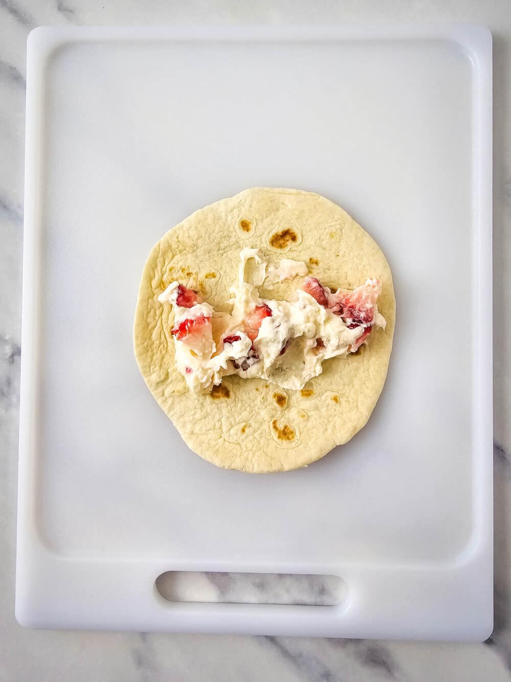 open face tortilla with strawberry cheesecake filling, showing how to fill