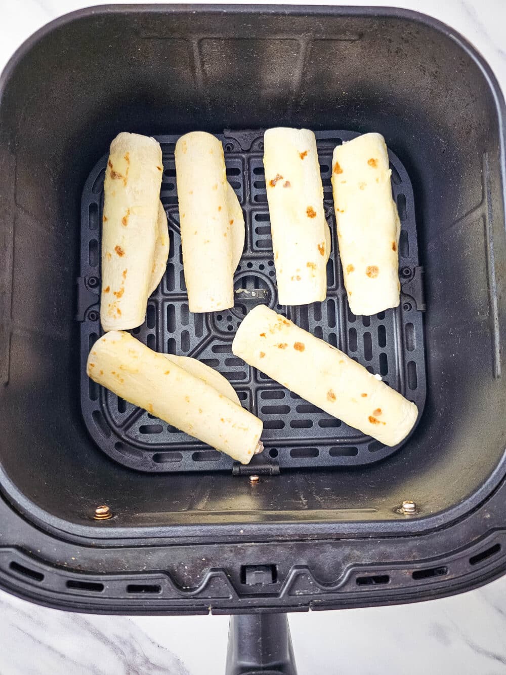 filled tortillas in an air fryer basket